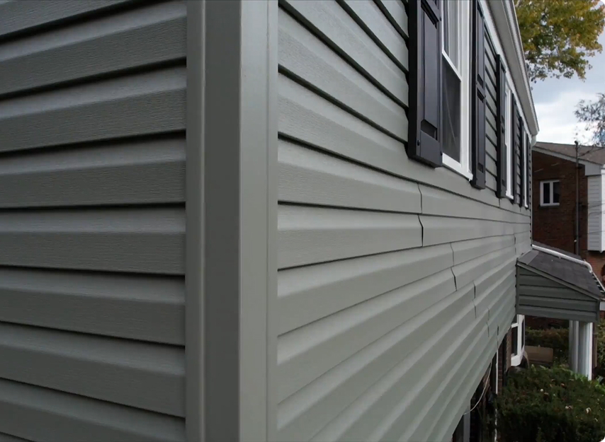 Buccos Roofing crew installing vinyl siding on a home