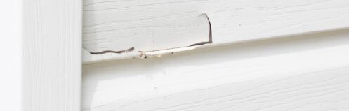 close up horizontal close up image of white siding with a big crack in it.