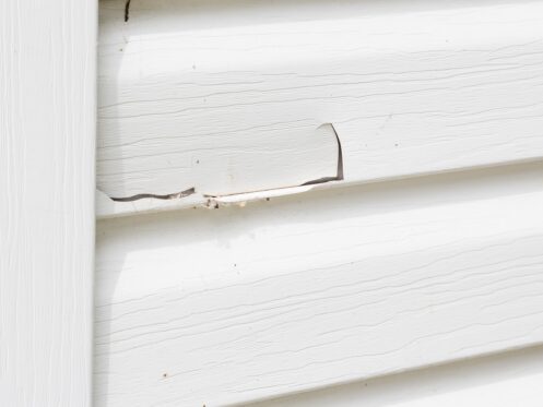 close up horizontal close up image of white siding with a big crack in it.