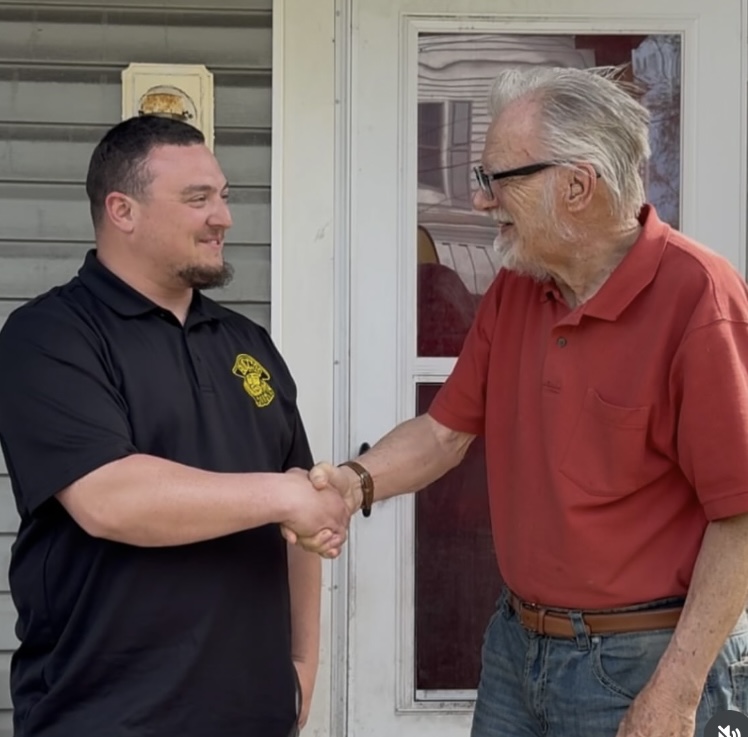 Buccos Roofing team member shaking hands with a previous recipient.