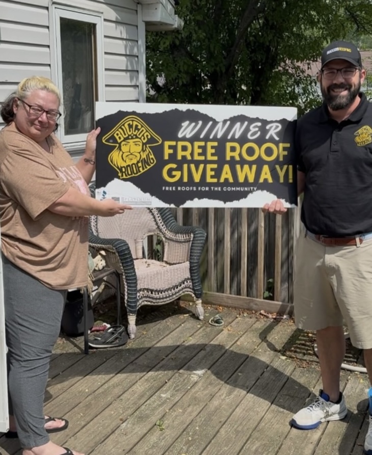 Previous Buccos Roofing giveaway winner holding a Free Roof Giveaway sign.