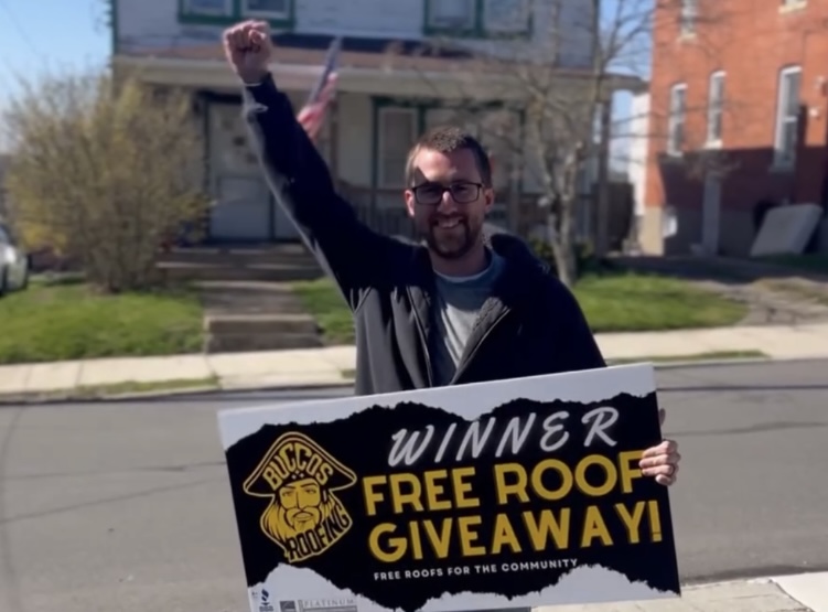 Previous Buccos Roofing giveaway winner holding a Free Roof Giveaway sign.